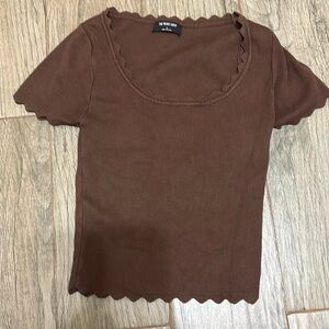 This is a brown thick material baby tee shirt with a wavy neck line